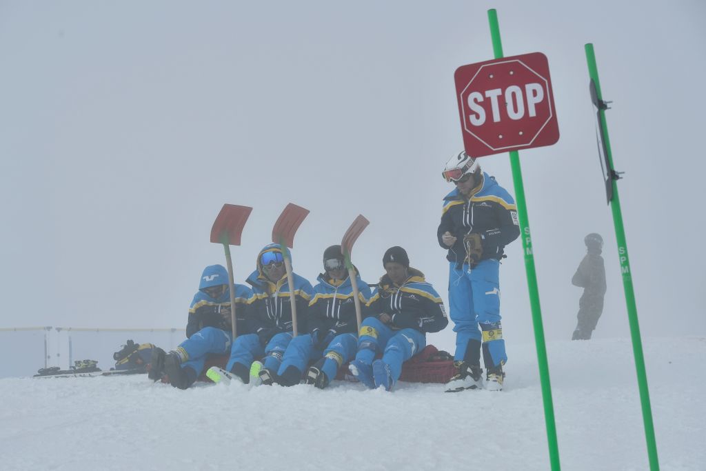 Officials sit on ski slope with shovels