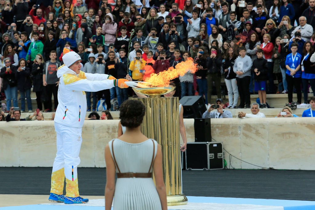 Ioannis Proios lights the Olympic torch during a handover ceremony for the Olympic Flame at Panathenaic stadium in Athens, on Tuesday, Oct. 31, 2017.