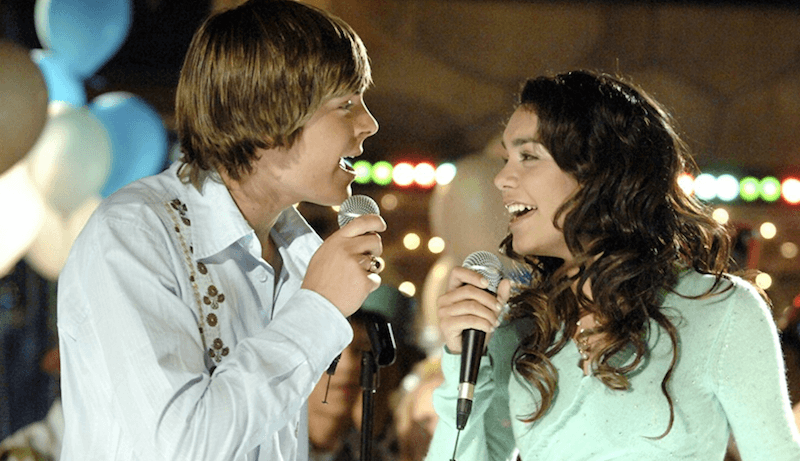 Troy and Gabriela sing into microphones at a party. Troy and Gabriela sing into microphones at a party.