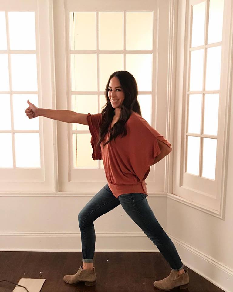Joanna Gaines with her bodysuit buttoned over her jeans holding a thumbs up.