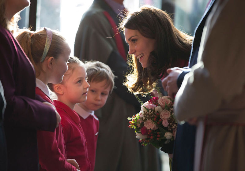 Kate Middleton smiling and speaking with children. 