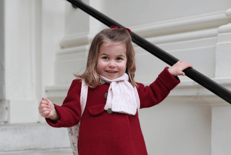 Princess Charlotte holds a railing as she climbs down a staircase. 