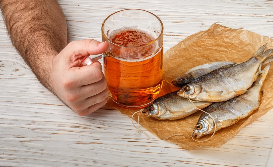 Male hand with a glass of beer and dry fish