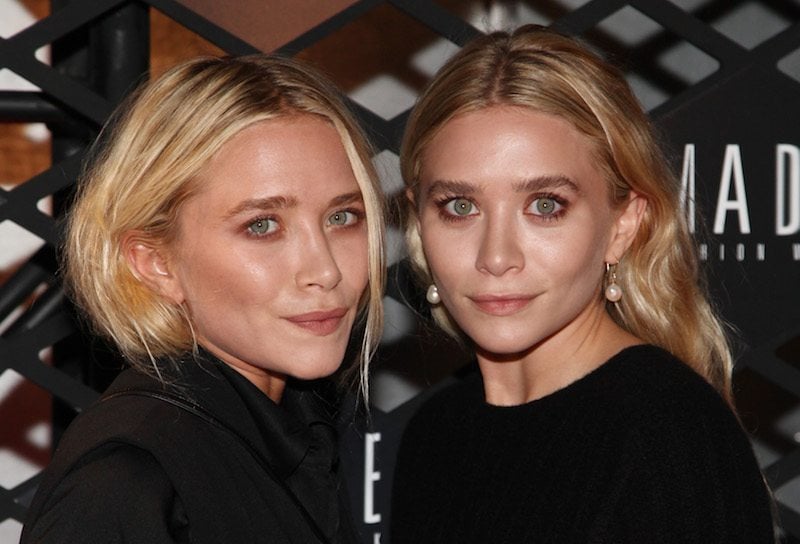 Mary-Kate Olsen and Ashley Olsen posing together while dressed in matching black outfits.