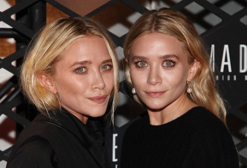 Mary-Kate Olsen and Ashley Olsen posing together while dressed in matching black outfits. Mary-Kate Olsen and Ashley Olsen posing together while dressed in matching black outfits.