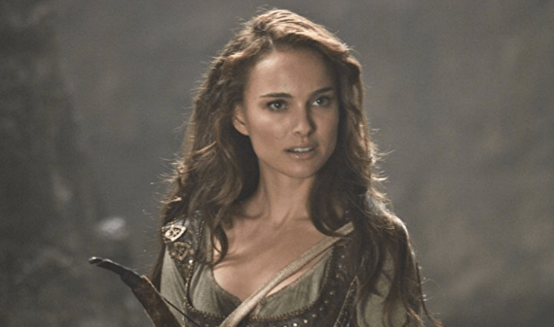 Natalie Portman holds a bow and arrow while standing in a forest. Natalie Portman holds a bow and arrow while standing in a forest.