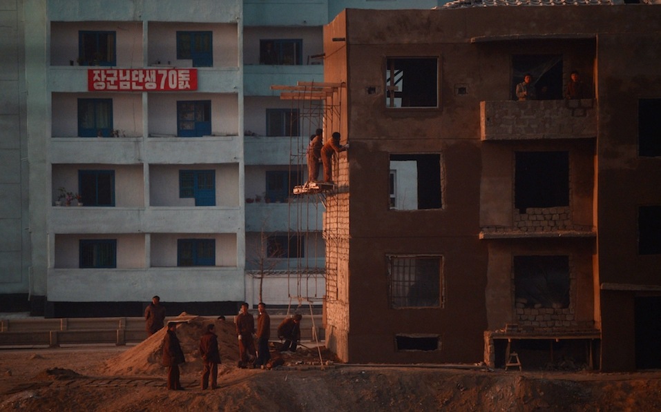 North Korean workers are seen from the window of a train as they work on a construction site along the railway