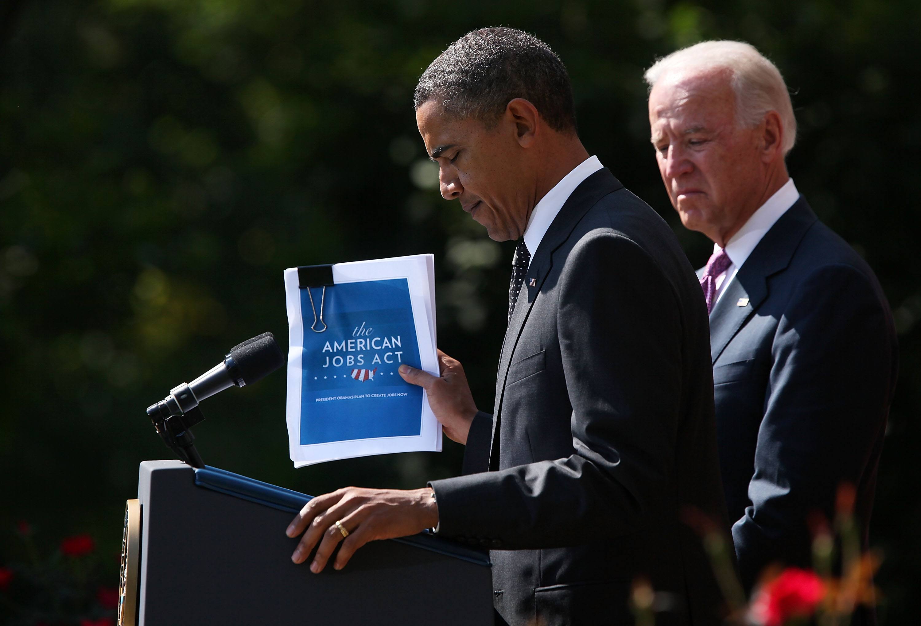 U.S. President Barack Obama holds up a copy of his $400 billion jobs plan he is sending to Congress as Vice President Joseph Biden stands next to him