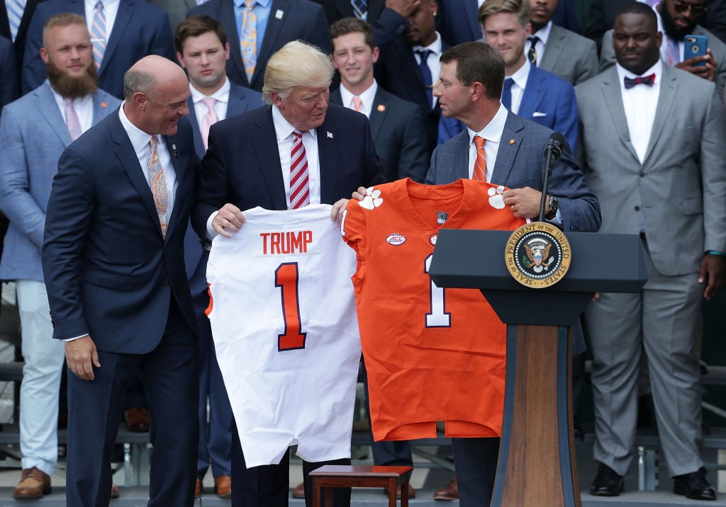 Clemson University President Jim Clements (L) and Clemson Tigers head coach Dabo Swinney (R) present two jerseys, one for President Donald Trump Clemson University President Jim Clements (L) and Clemson Tigers head coach Dabo Swinney (R) present two jerseys, one for President Donald Trump