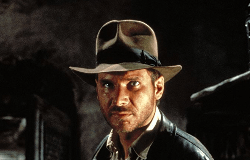 Indiana Jones looking straight ahead while wearing a hat and jacket. 