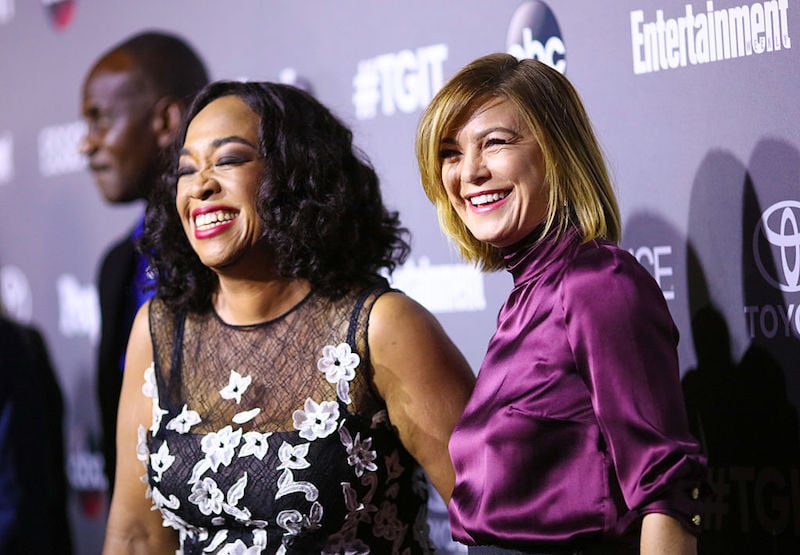 Shonda Rhimes and Ellen Pompeo smiling together on the red carpet.