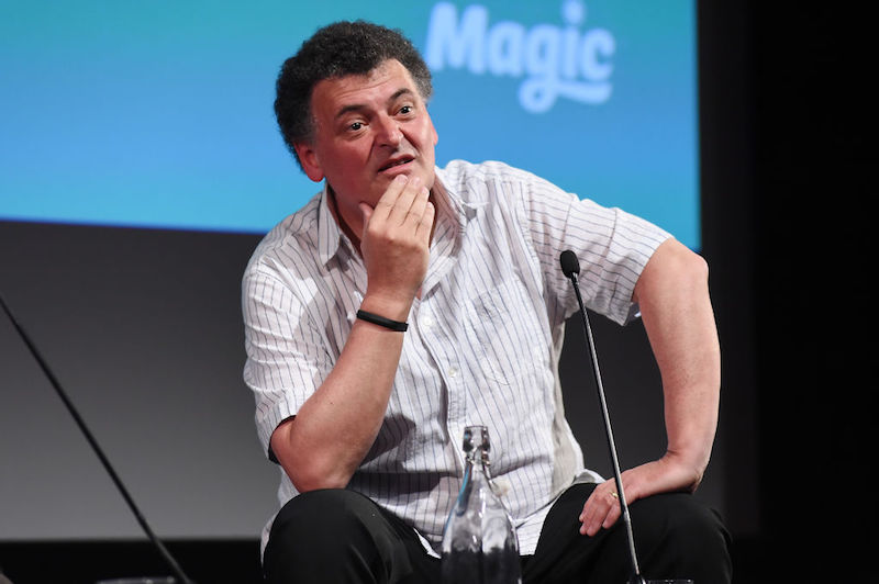 Steven Moffat sitting in front of a microphone on stage. Steven Moffat sitting in front of a microphone on stage.