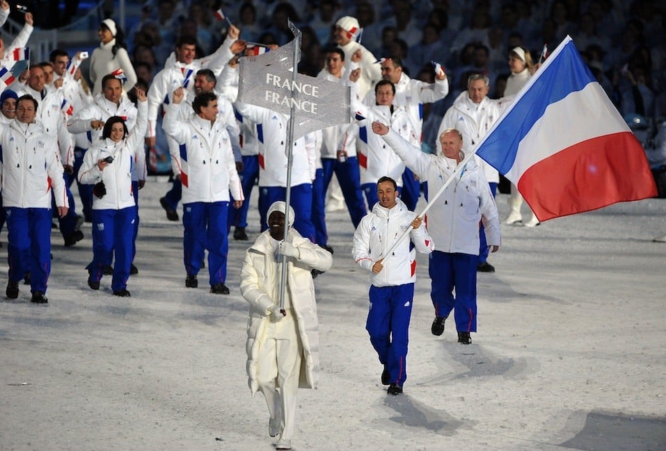 The French delegation, led by flagbearer, biathlon athlete Vincent Defrasne, enter the stadium