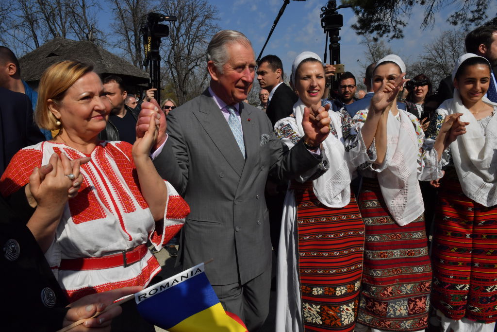 Prince Charles, Prince of Wales dances with Romanian dancers at a village museum on the second day of his nine day European tour