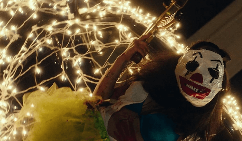 A woman wearing a mask holds a gun upwards. A woman wearing a mask holds a gun upwards.