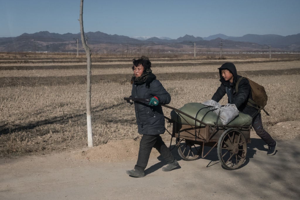A woman and child pull a cart loaded with wood along a road near Kiliju on North Korea's northeast coast