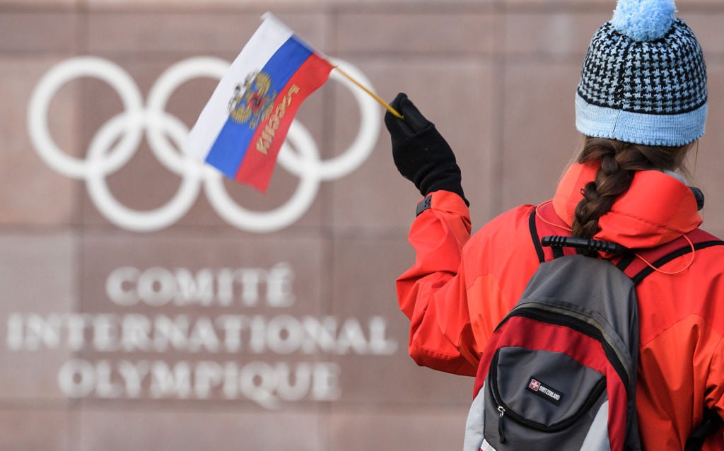 A supporter waves a Russian flag in front of the logo of the International Olympic Committee