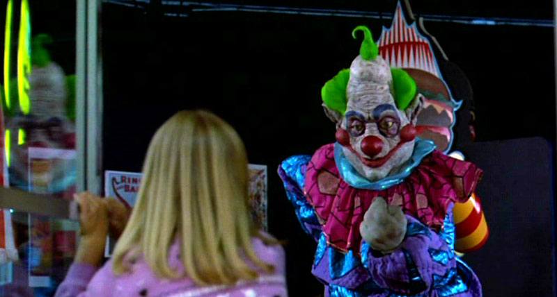 A scary clown looks at a blonde child