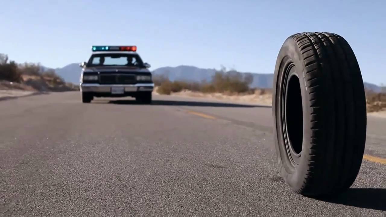 a rubber tire on a road behind a cop car a rubber tire on a road behind a cop car