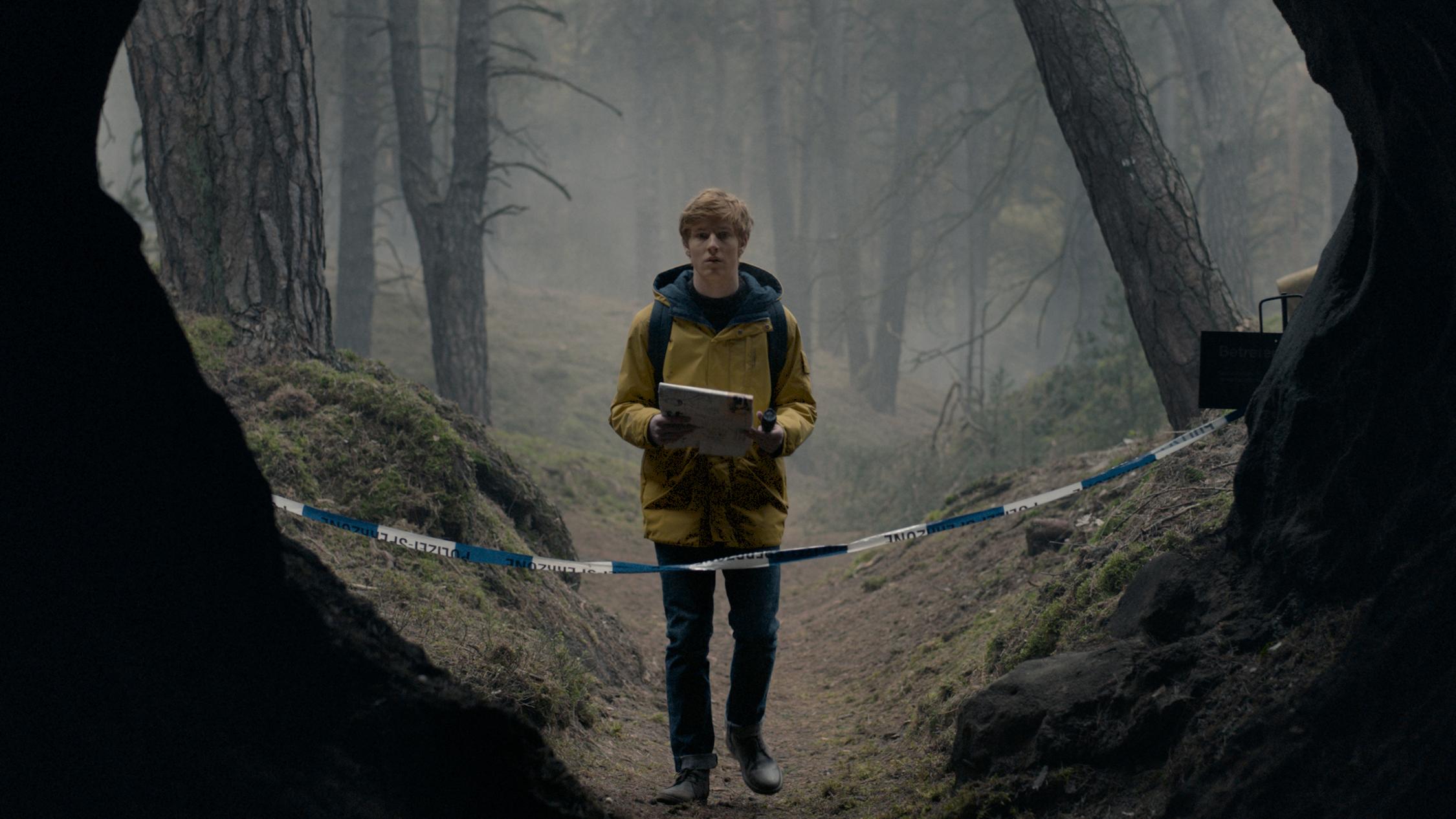 A boy stands in woods