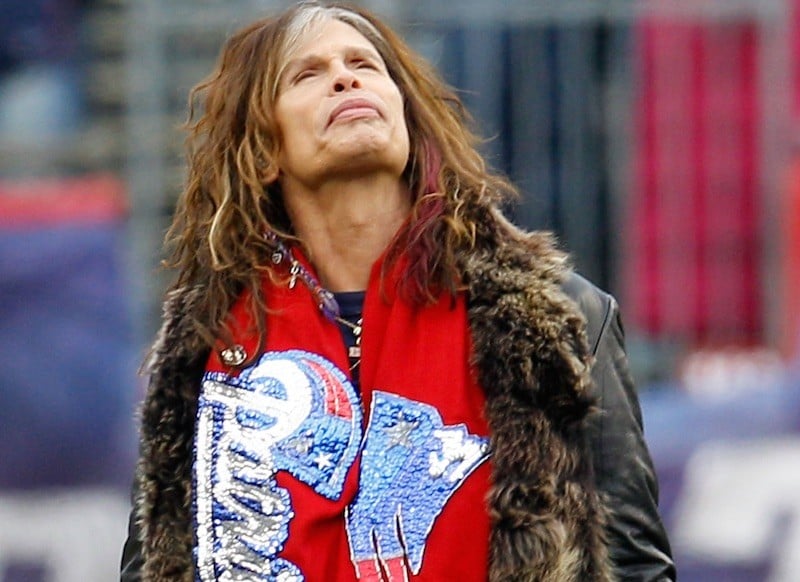 Steven Tyler looks up while wearing a red patriots scarf