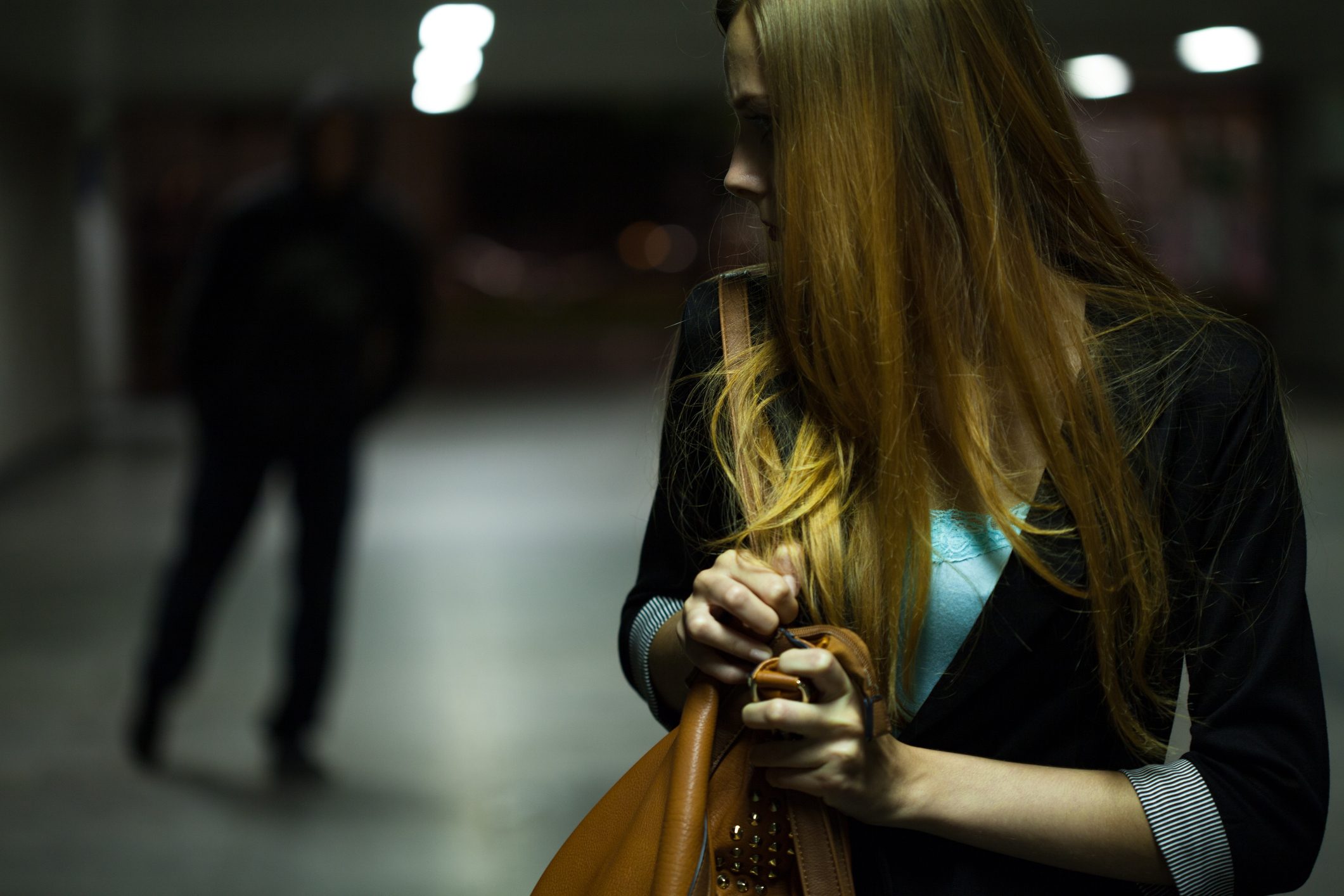 Scared woman with shadowed man walking behind her