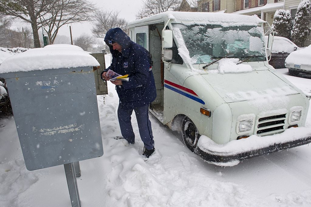 A US Postal Service carrier delivers mail during a snow storm.