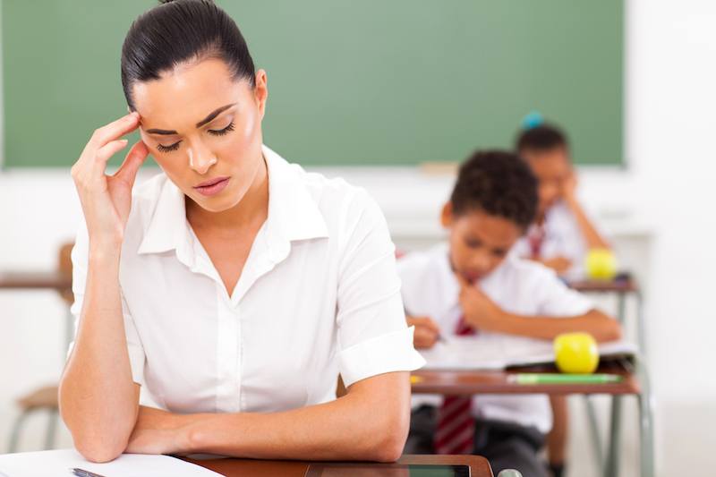 primary teacher having headache in classroom