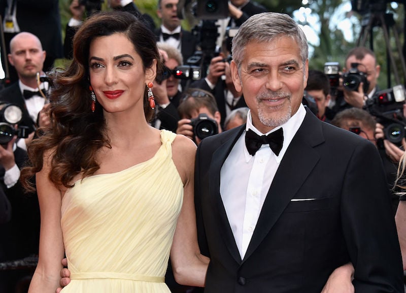 Amal Clooney holding George Clooney's back. 