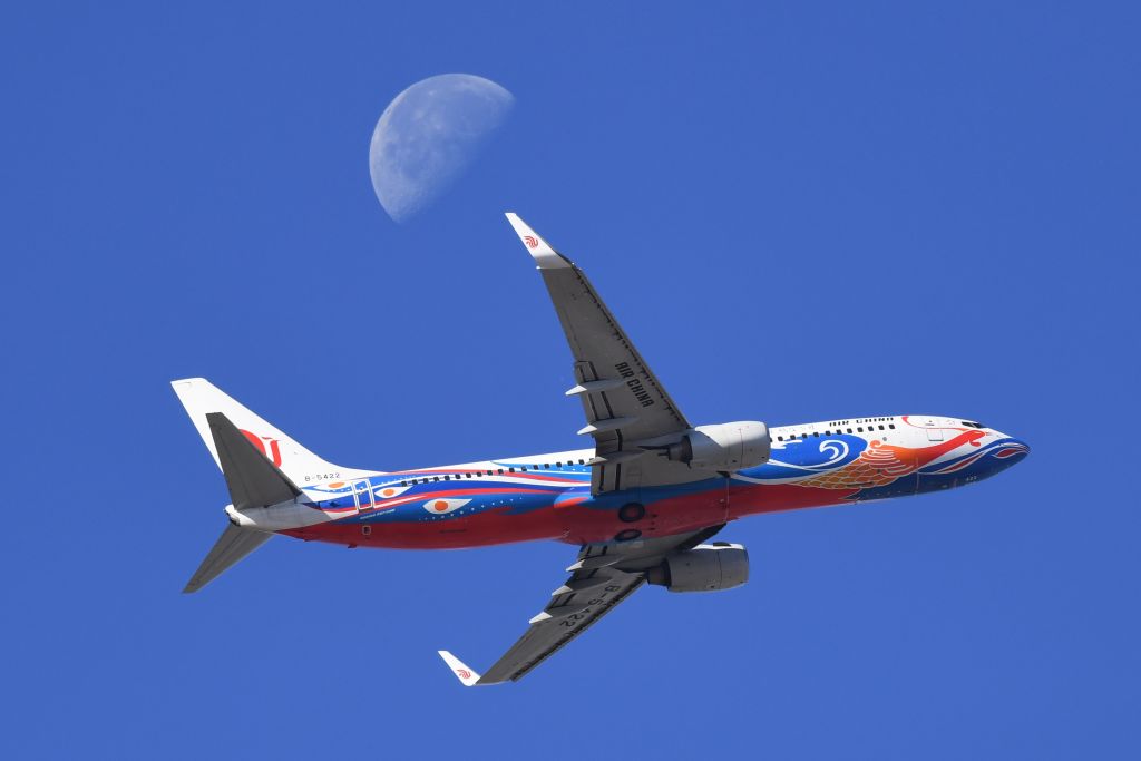 An Air China plane flies in front of the moon