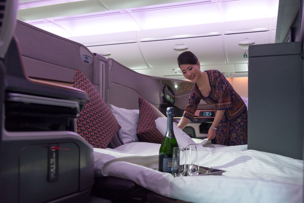 An air stewardess arranges bedsheets of a double bed