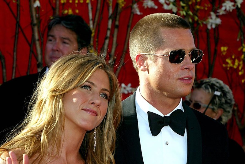 Jennifer Aniston smiling and waving as she poses with Brad Pitt. Jennifer Aniston smiling and waving as she poses with Brad Pitt.