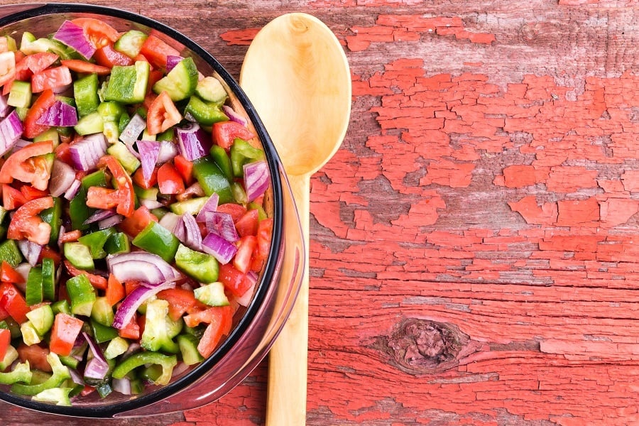 A large salad of veggies next to a wooden spoon A large salad of veggies next to a wooden spoon