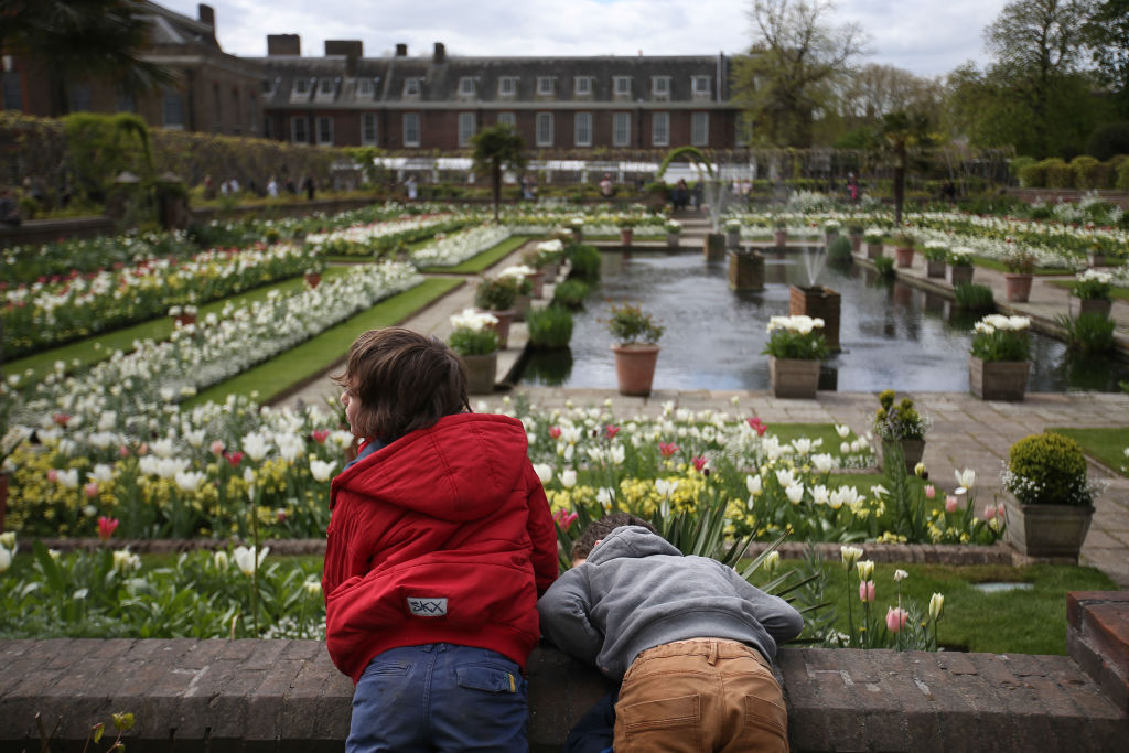 Children lean over the wall outside the White Garden, created to celebrate the life of Diana