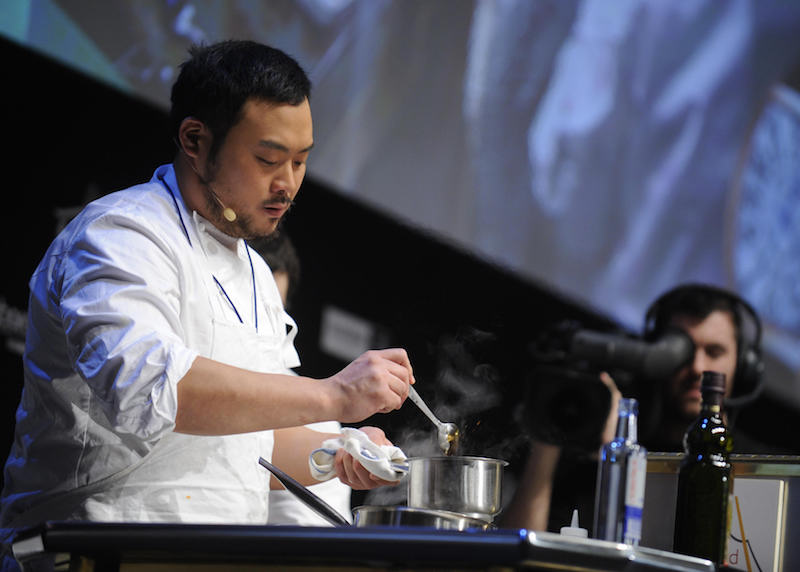 David Chang stirring the ingredients in a small silver pot. 