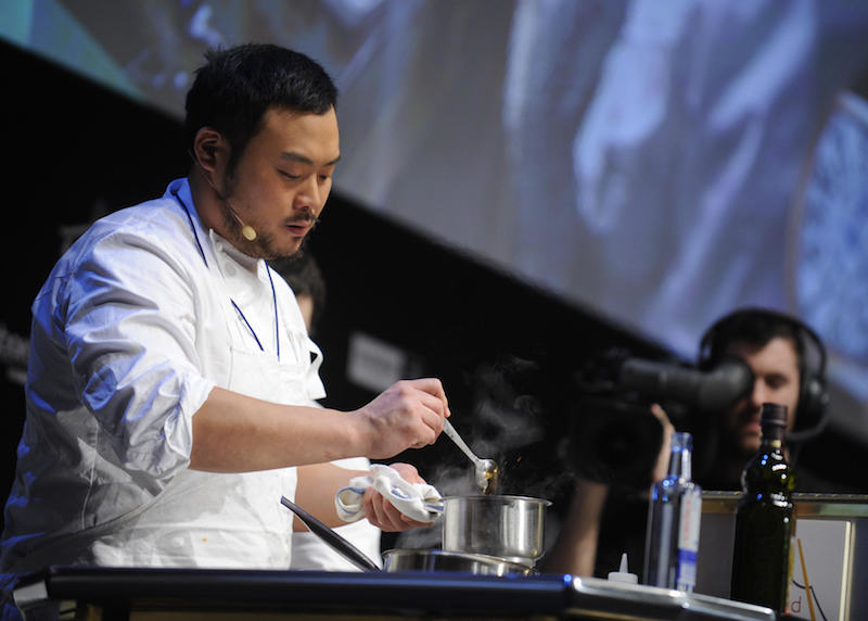 David Chang stirring the ingredients in a small silver pot. David Chang stirring the ingredients in a small silver pot.
