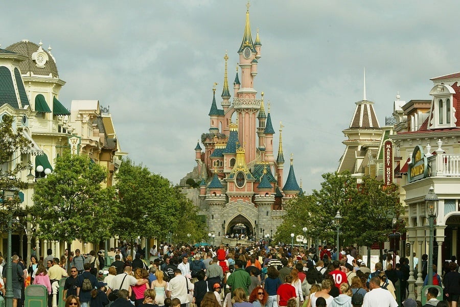 A crowd of tourists walk toward the Sleeping Beauty castle