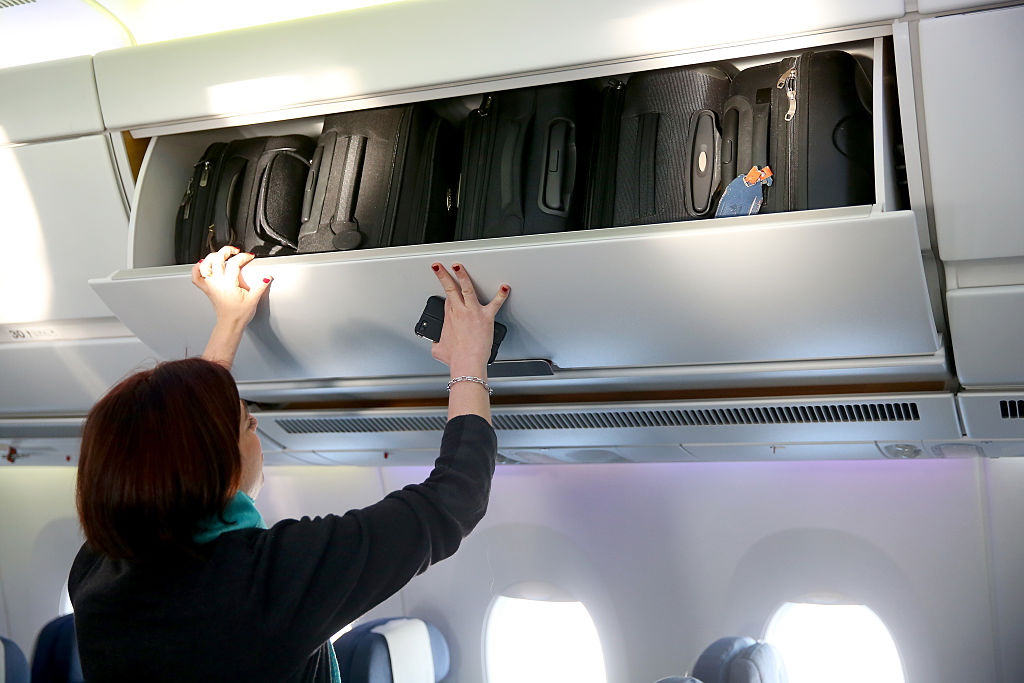 hand baggage overhead bin putting bags in overhead bin
