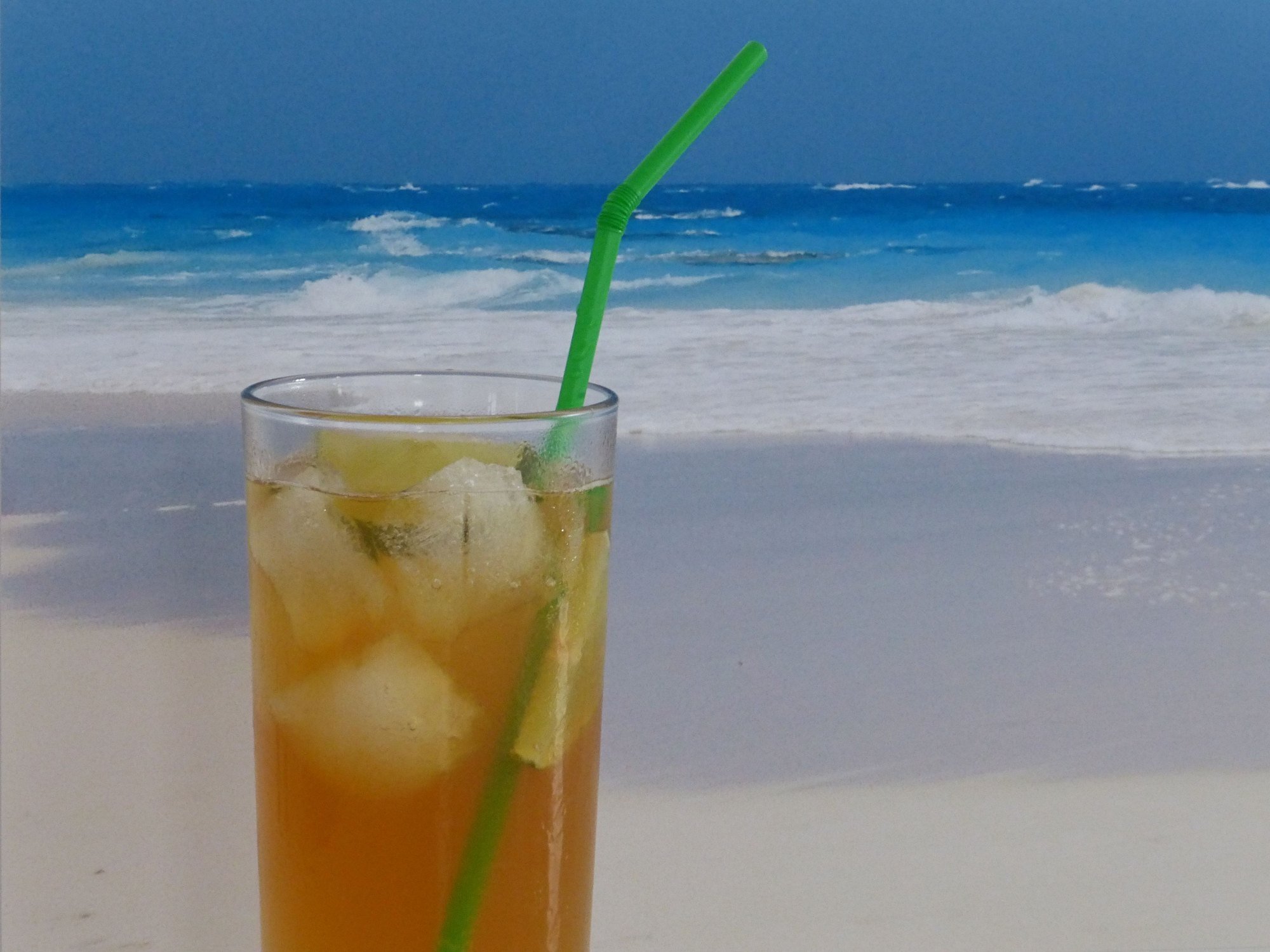 dark n stormy cocktail in front of a beach