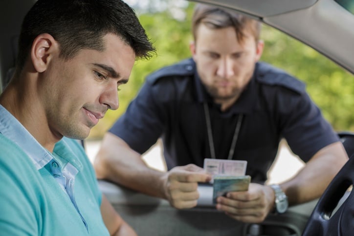 Shot of a young driver and a policeman checking his driving licence Shot of a young driver and a policeman checking his driving licence
