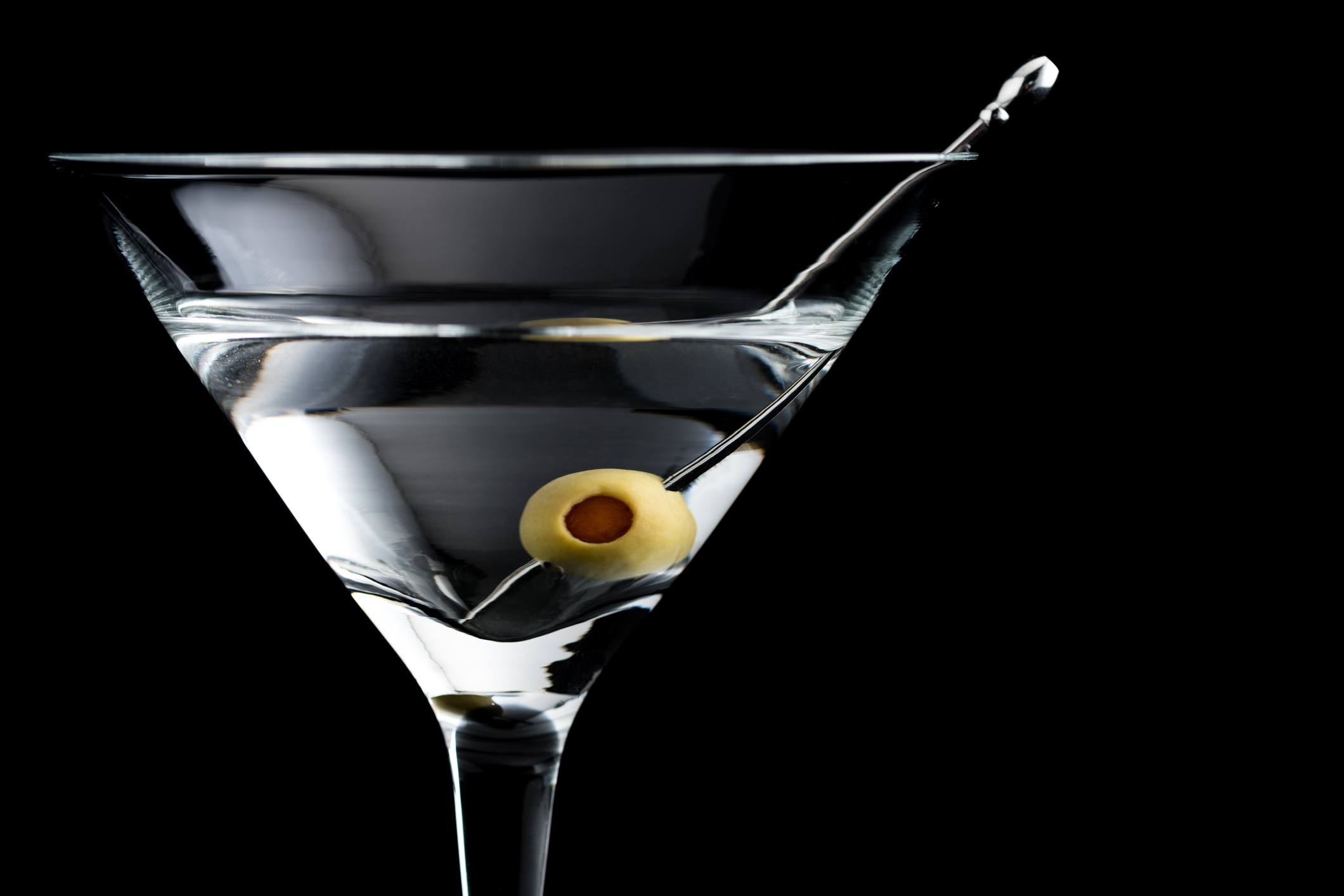 Vodka martin cocktail with olives on black background