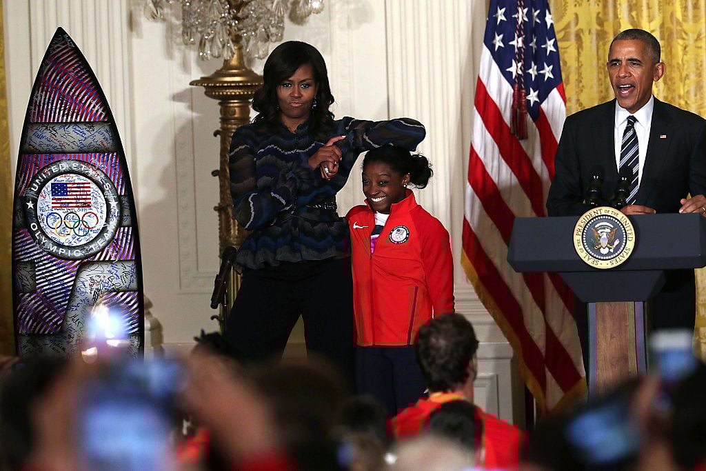 Michelle Obama rests her elbow on the head of Olympian Simone Biles