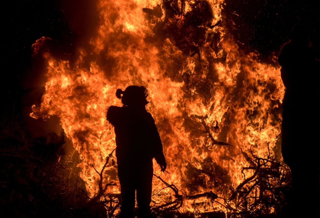 a woman in front of a raging bonfire a woman in front of a raging bonfire