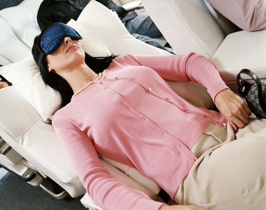 Woman sleeping in aeroplane with eye mask