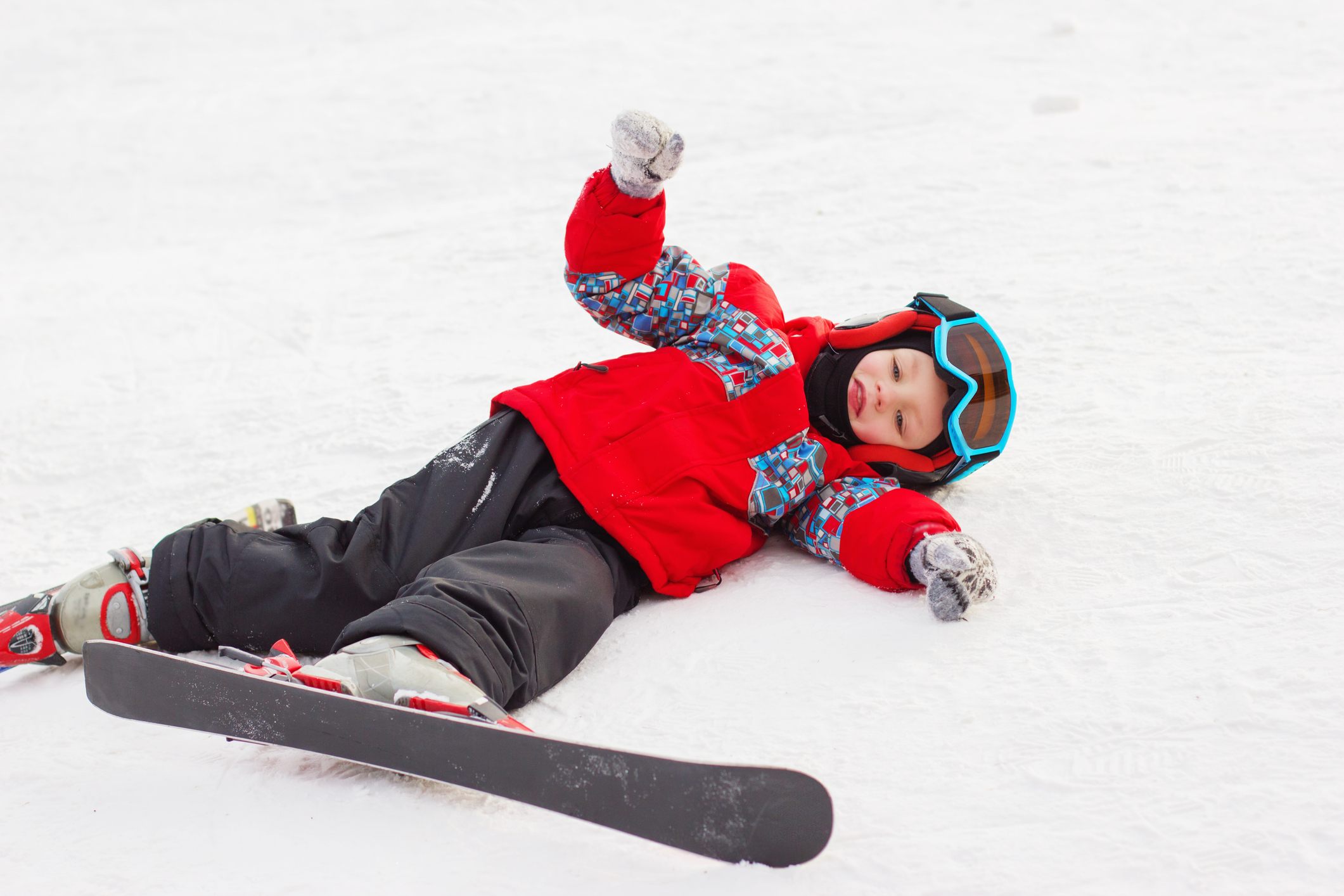 Little cute boy with skis and a ski outfit.