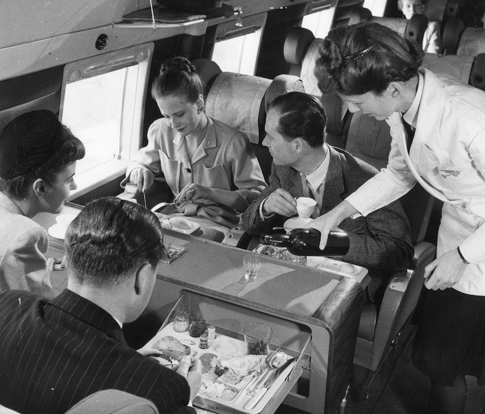A stewardess serving drinks whilst passengers have lunch aboard a BEA Vickers Viking passenger plane