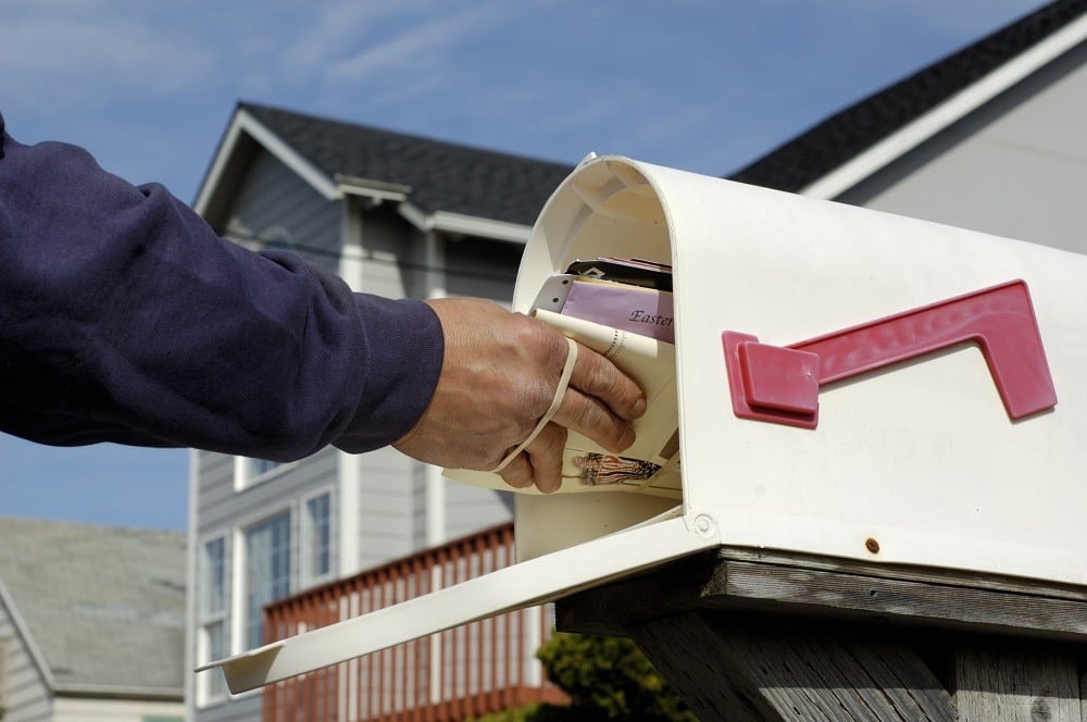 Mailman's arm inserting a bundle of mail