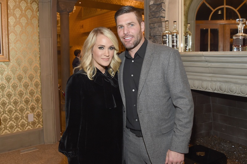 Mike Fisher and Carrie Underwood posing in front of a fireplace. 