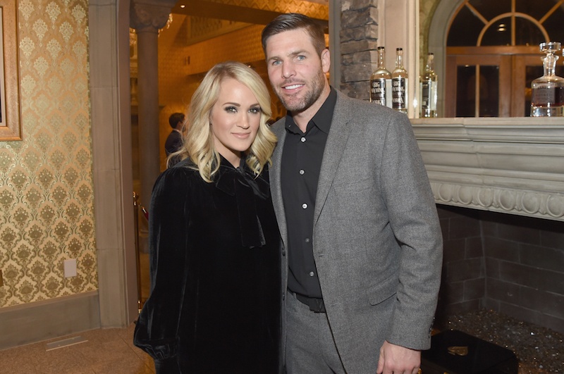 Mike Fisher and Carrie Underwood posing in front of a fireplace. Mike Fisher and Carrie Underwood posing in front of a fireplace.