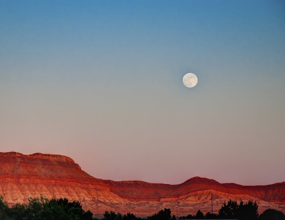 Full moon rising over the mountains of St. George Utah.